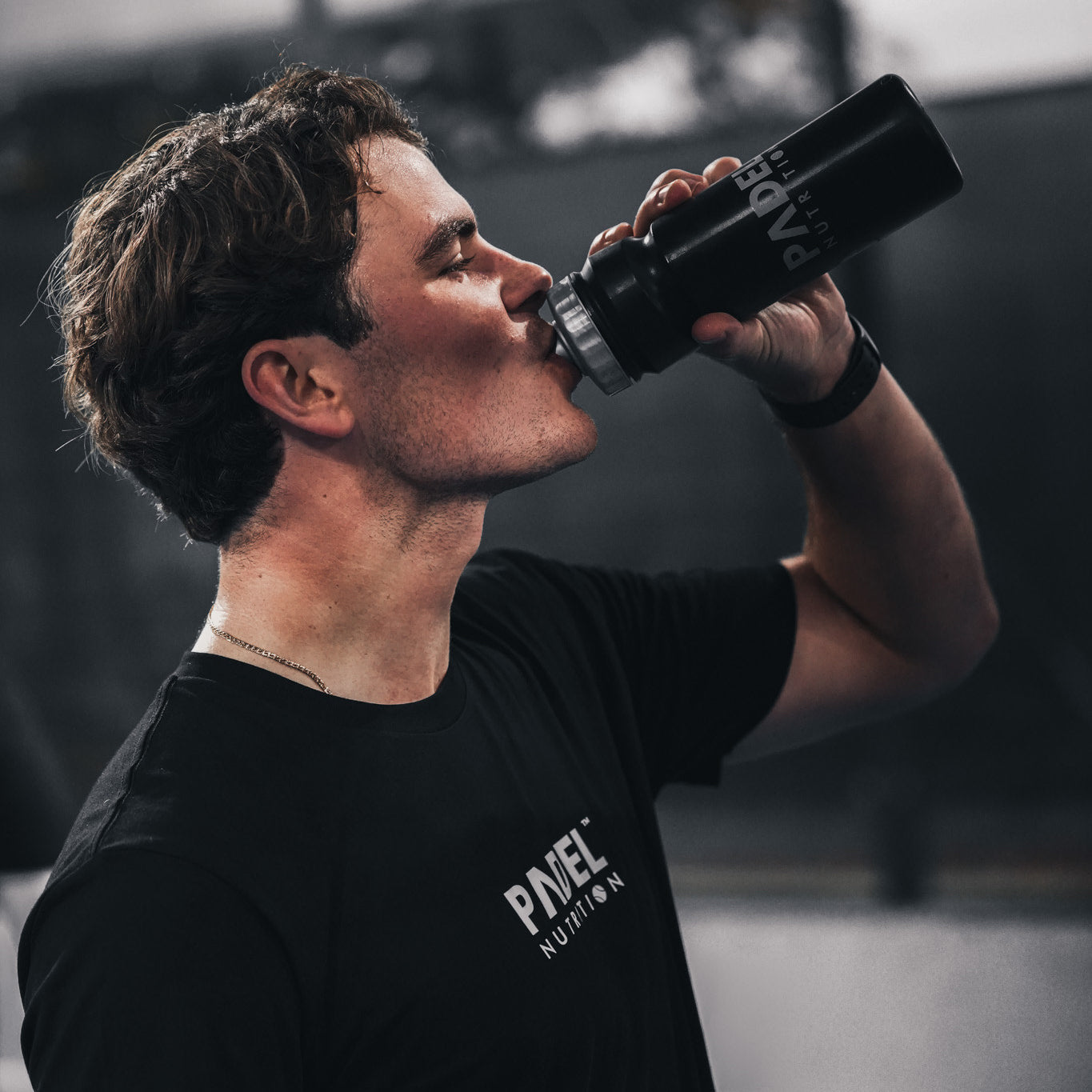 padel player resting after a match with a drink showing the importance of recovery and hydration for performance